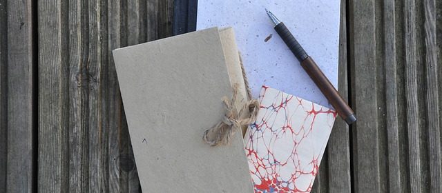 Tre böcker överlappar varandra. Ovanpå dessa ligger en penna.