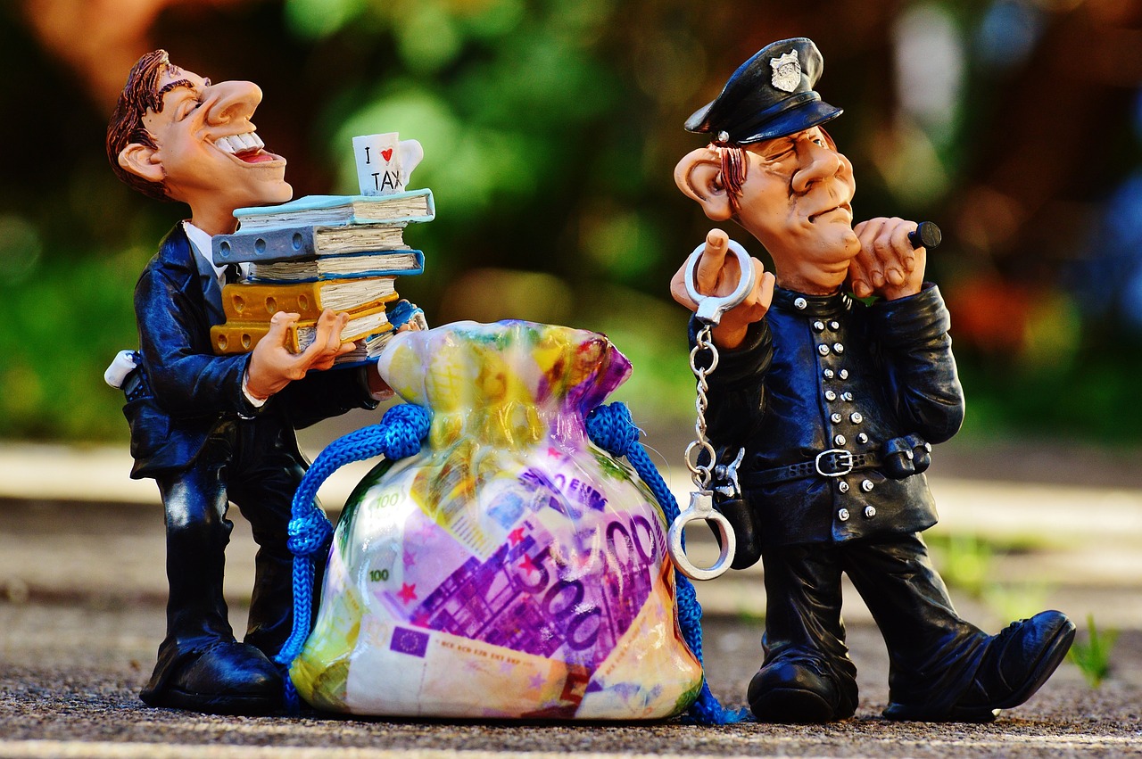 Tre statyetter föreställande person hållande böcker, säck med Euros och en tänkande polis.