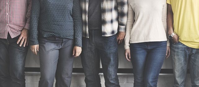 Fem personer står skuldra mot skuldra men deras huvuden är bortskurna från bilden