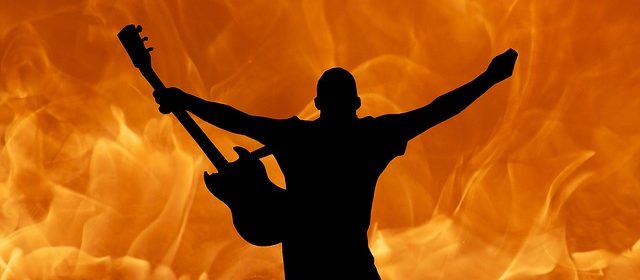 Person med elgitarr framför eld