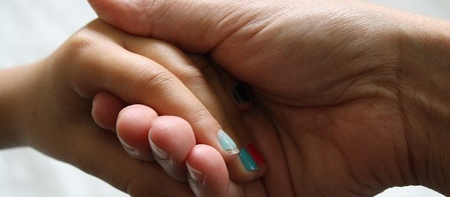 Föreläsning - Min dotter har en hjärnskada. (dekorativ bild av barns hand i kvinnas hand)