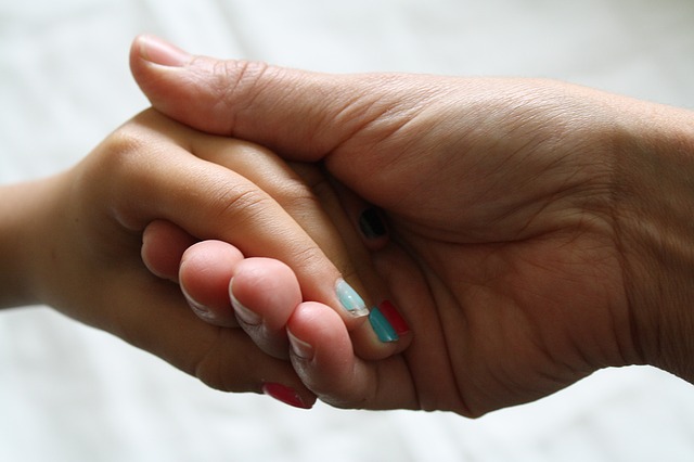 Föreläsning - Min dotter har en hjärnskada. (dekorativ bild av barns hand i kvinnas hand)
